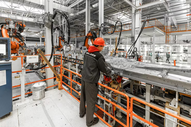 Opérateur en atelier automobile travaillant sur une caisse de véhicule le long d'une chaîne d'assemblage robotisée